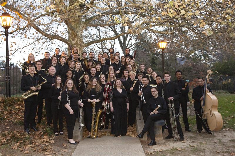the UD wind ensemble standing on the green holding instruments