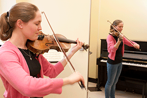 student playing violin in a practice room