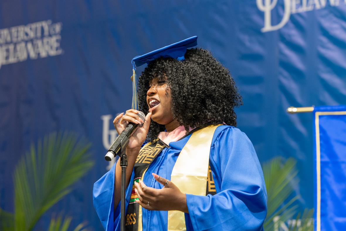 woman in academic regalia singing