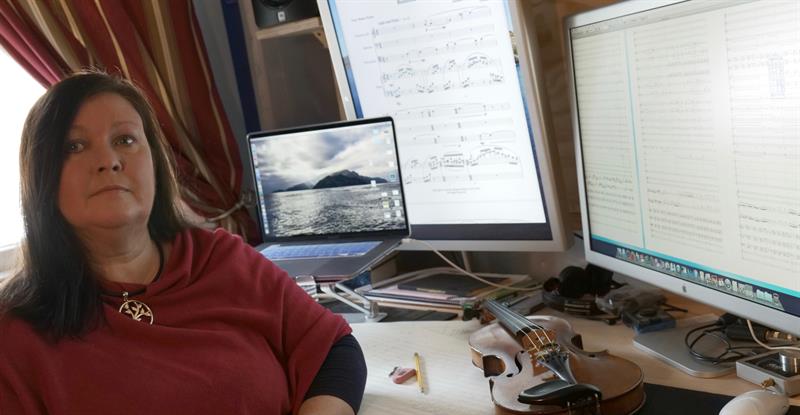 Jennifer Margaret Barker poses in front of her musical composition notes seen on her laptop and external monitors.