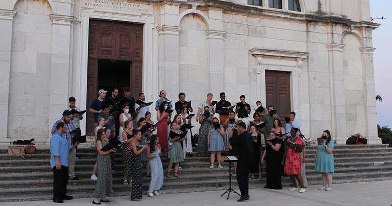 University of Delaware Chorale sing on the steps of a building