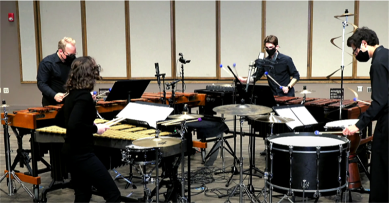 four students playing percussion instruments