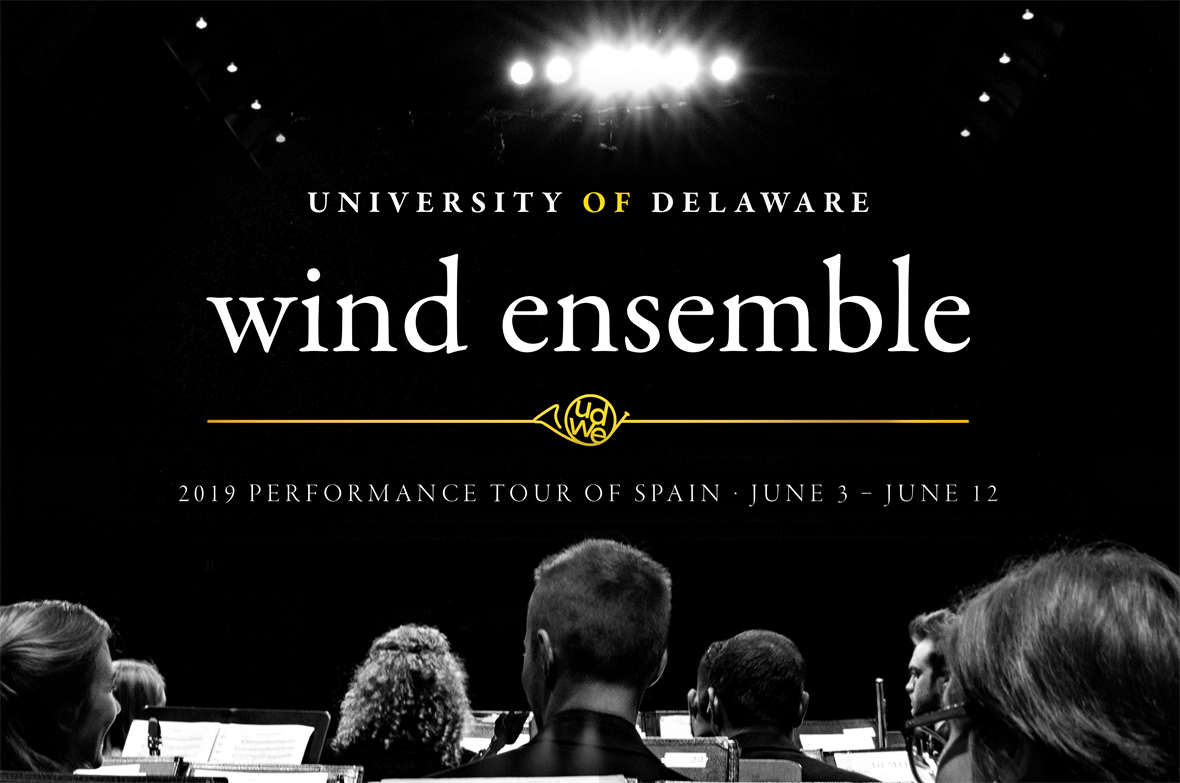 A black and white image of the back of the heads of 7 musicians. They are facing a spotlight. The text reads "University of Delaware Wind Ensemble Performance Tour of Spain - June 3 - June 12"